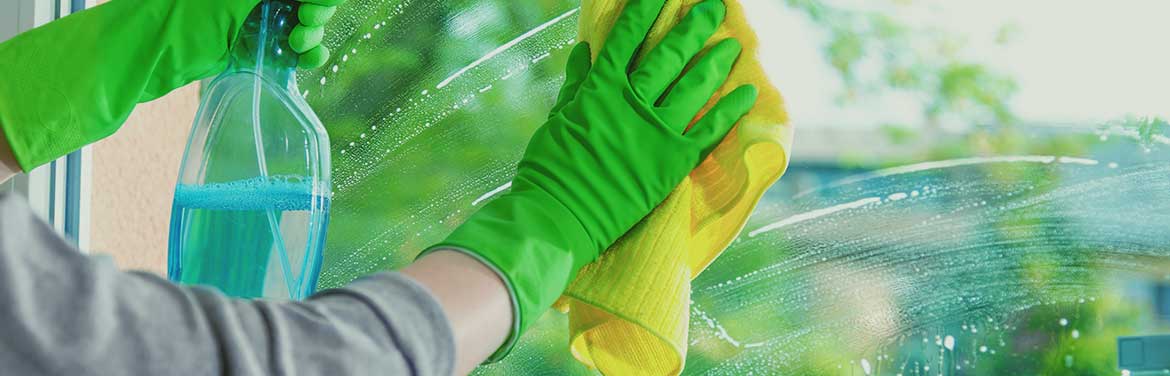 person with green rubber gloves cleaning a window