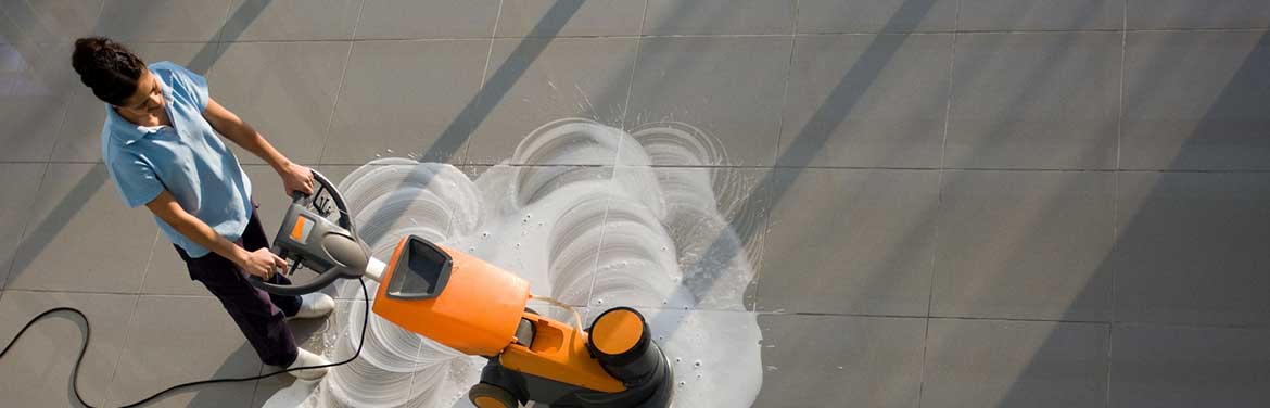 woman cleaning tile floor with buffing machine