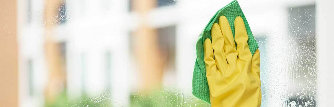 hand in green rubber glove washing window